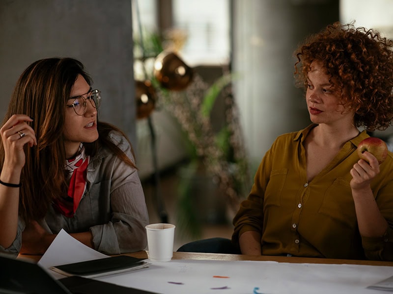 Two colleagues discussing feedback and learning – developing a growth mindset to overcome workplace challenges.
