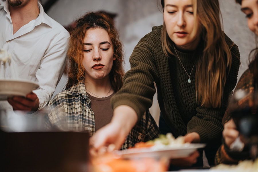 Young Australian woman at a shared meal with friends, showing food-related anxiety and a complex relationship with food in Australia.