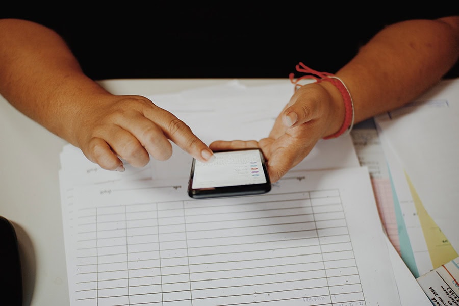 Support worker reviewing behaviour records on a phone for NDIS social and community participation supports