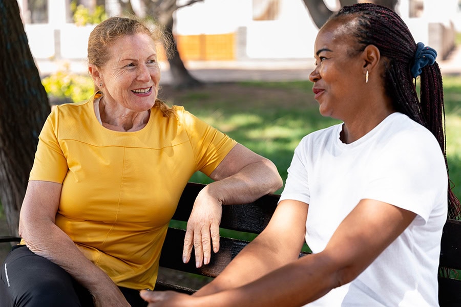 An NDIS behaviour support practitioner and a participant having a relaxed conversation on a park bench